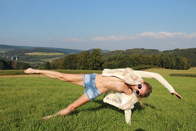 Yogalehrerin Elke in einer Variation der seitlichen Planke auf einer Wiese.